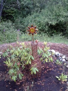 This sun, star, and planet sparkler was fitted through the bottom of an Indian inspired openwork metal basket. We nestled it into the rhododendron. When it blooms purple next spring it should be spectacular. 